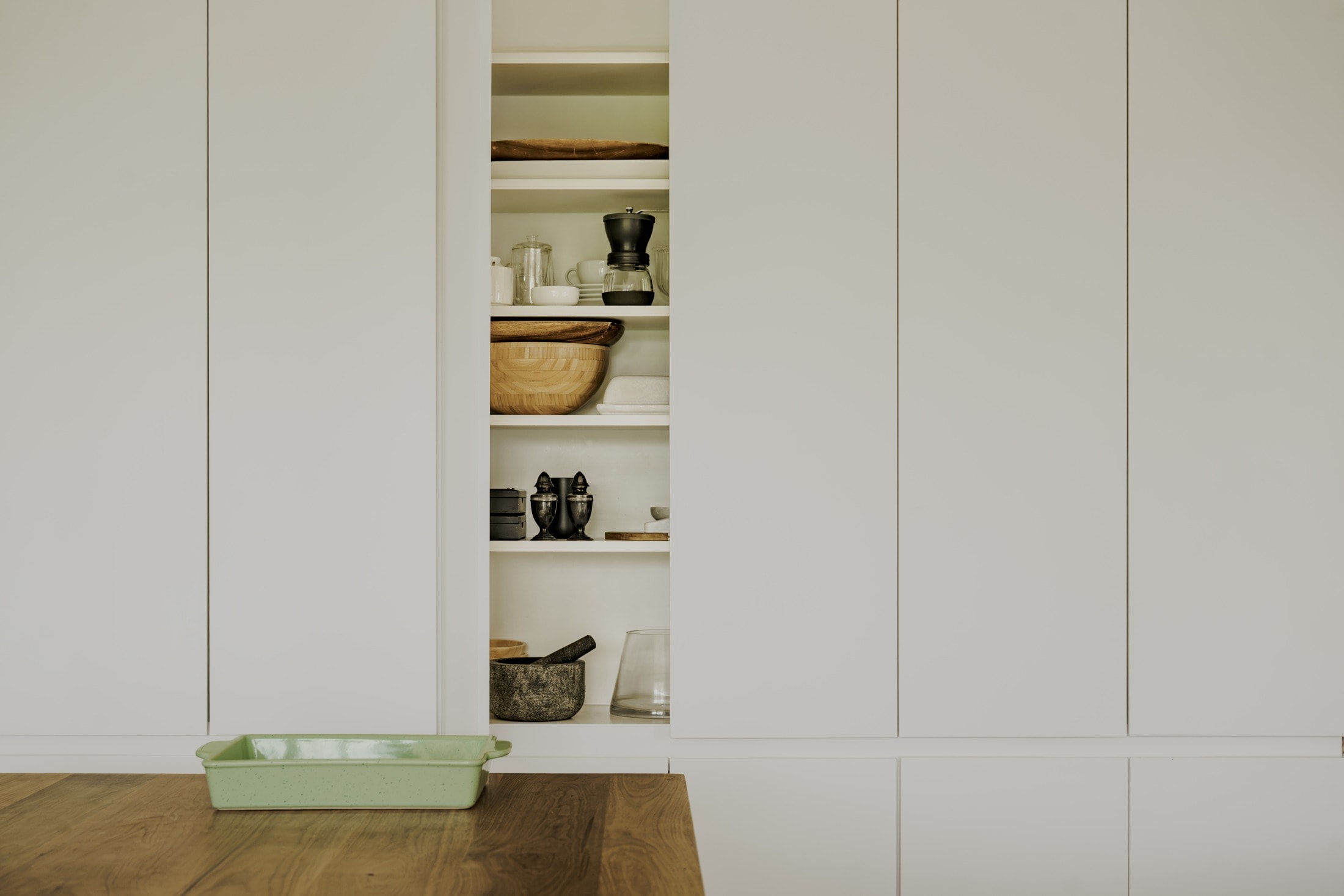 White kitchen cabinet fronts with open door revealing interior shelving, Bryant Avenue