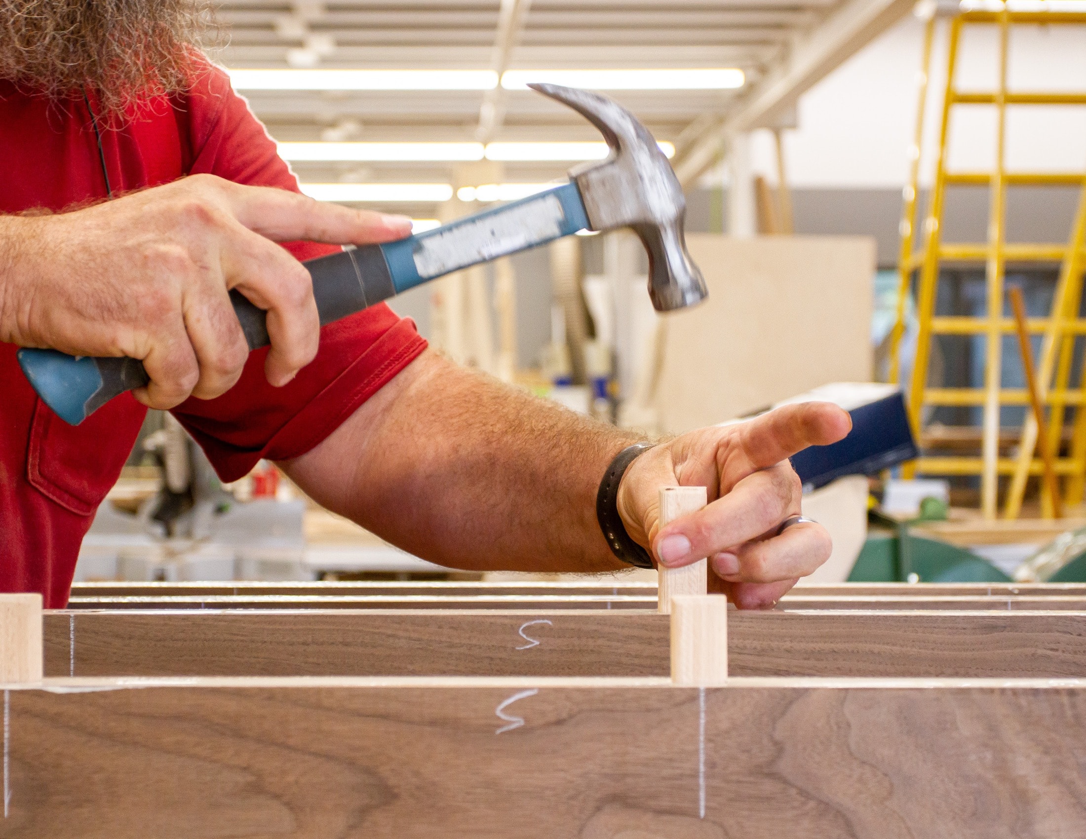 Craftsman assembling a wood frame joint with a hammer in the fabrication shop
