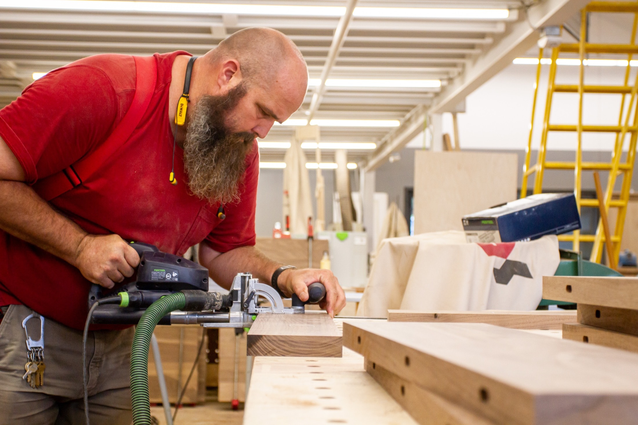 Craftsman using a biscuit joiner on wood panels in the fabrication shop